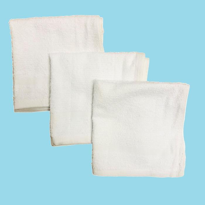 Three folded white cotton washcloths on a blue background.